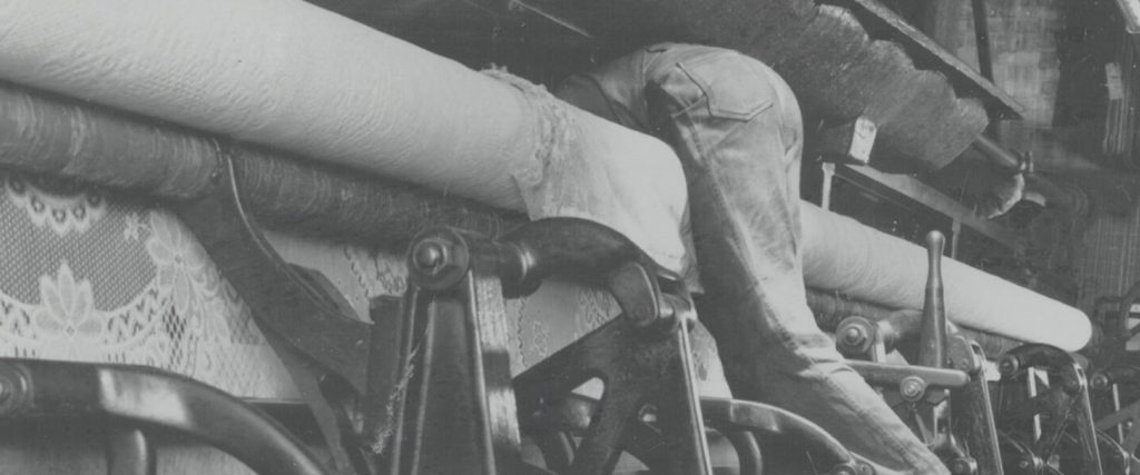 Person clambering between some reels of fabric